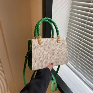 Chic beige straw tote bag with green leather trim and woven handles in a bright room