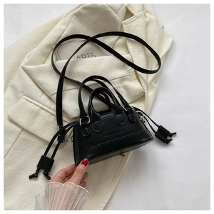 Detail of a mini black shell crossbody bag with dual handles on a stylish blazer