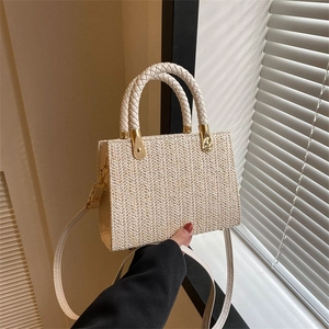 Beige straw tote bag with herringbone weave, round handles and gold hardware details