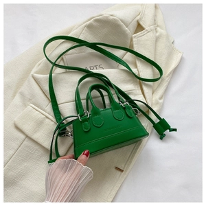 Macro detail of emerald green mini shell bag featuring fashion text and fine stitching