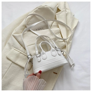 Close-up of white mini shell bag with FASHION & BAGS embossing and tassel detail