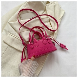 Detailed macro of a hot pink mini shell bag with PU leather texture and metal handle strap