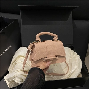 Macro view of light pink pebble grain leather mini bag with gold-tone metal hardware