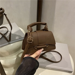 Detail of dark brown lychee leather mini handbag with gold ring buckle and thick handle