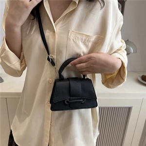 Detailed view of a black mini crossbody bag with litchi texture and top handle