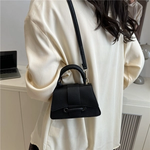 Detail of black pebbled leather mini crossbody bag with top handle and strap shown on model
