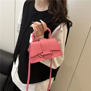Detail of pink pebbled leather handbag featuring decorative strap and metal eyelets