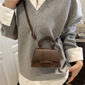 Close-up of brown litchi-textured mini crossbody bag with a sleek trapezoid shape