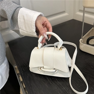 Detail showing white mini trapezoid bag with pebble texture leather and curved base