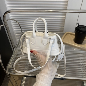 Mini white shell bag with embossed fashion text and drawstring liner on a metal stand