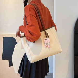 Minimalist beige tote bag with brown straps and cute monster charm shown on a model