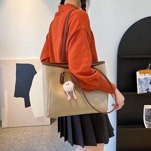 Minimalist large capacity leather tote bag in beige with monster plush pendant on shoulder