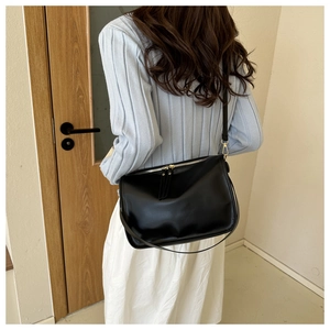 Lifestyle shot of black minimalist tote bag worn as crossbody with gold zipper detail
