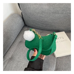 Detail of green tweed crossbody bag with diagonal quilting and white pompom charm