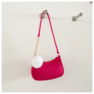 Detail of rose pink quilted crossbody bag with golden chain and white pompom charm