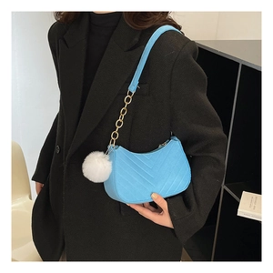 Detail of light blue crescent bag with V-shaped quilting and white fur pompom charm