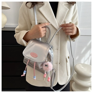 Detail of silver metallic bucket bag with pink plush keychain and beaded drawstring