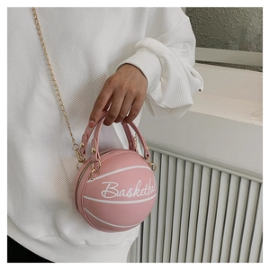 Détail d'un sac à bandoulière rose en forme de basket avec chaîne dorée et deux poignées