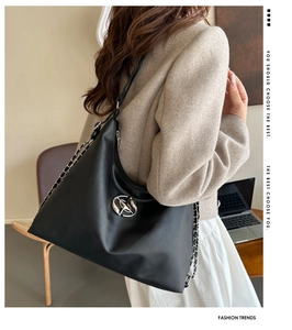 Detail of black leather hobo bag with silver buckle and metal chain strap in daily use