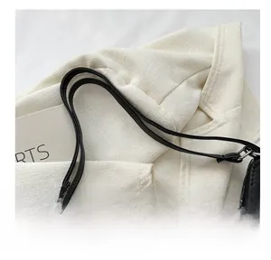 Detail of slim black faux leather handle with silver metal rings on a shoulder bag