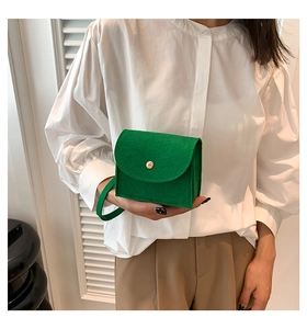 Detail view of mini green felt handbag with gold snap button and stylish square design