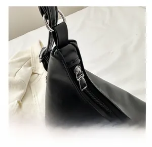 Close-up of a smooth silver metal zipper on a textured black leather bag detail