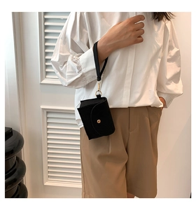 Detail of a black felt mini wristlet bag with gold hardware and envelope flap design