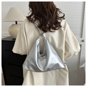 Close-up of the silver metallic hobo bag with an abstract metal logo and leather strap