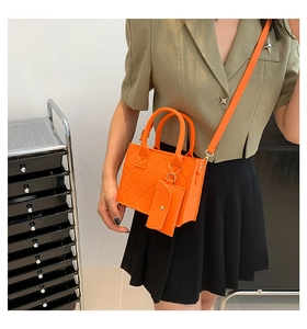 Detailed shot of an orange quilted felt bag with crossbody strap and small charm