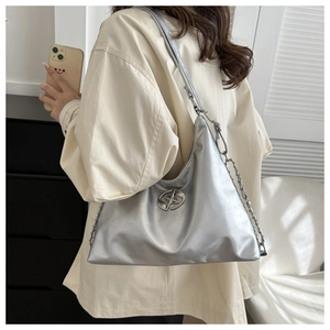 Metallic silver tote bag detail featuring a unique round metal logo and chain strap