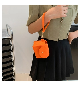 Close-up of bright orange felt pouch with gold metal snap button and wrist strap detail