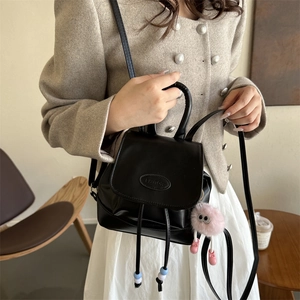 Minimalist black leather mini backpack for women with drawstring and plush monster charm