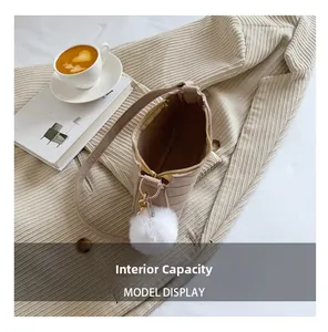 Detail view of the beige canvas handbag interior with a soft white pompom accessory