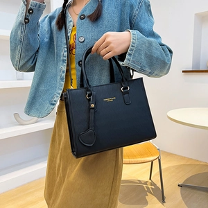 Borsa tote nera trapuntata con ciondolo a cuore e dettagli dorati indossata dal modello