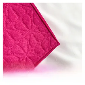 Detail of rose red felt fabric with embossed teardrop patterns and neat edge stitching