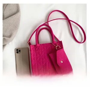 Detail of rose red felt handbag set with embossed heart patterns and a small matching pouch