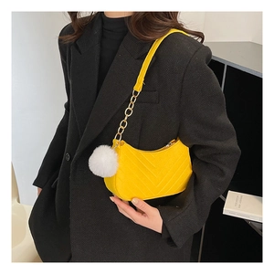 Detail of bright yellow quilted shoulder bag with gold chain and white fur charm