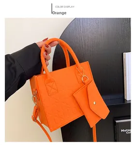 Detail of vibrant orange felt handbag showing geometric texture and mini pouch