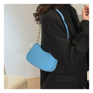 Close-up of light blue quilted shoulder bag with gold chain and white fur ball detail