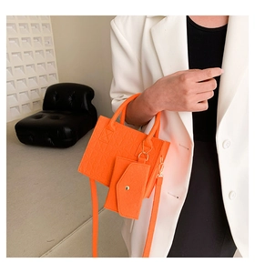 Bright orange tote bag set with geometric texture and small purse worn with white suit