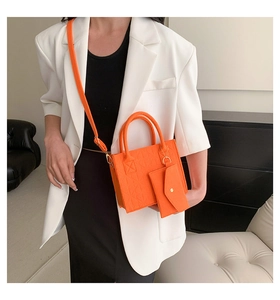 Detail of orange felt handbag featuring embossed heart patterns and a matching mini pouch