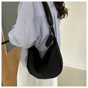 Side view of black nylon crescent bag featuring a wide shoulder strap and a round coin pouch