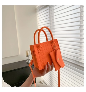 Detail of orange felt handbag with embossed texture and matching mini pouch accessory