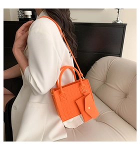 Detail of bright orange felt tote bag set with geometric texture on cream sofa