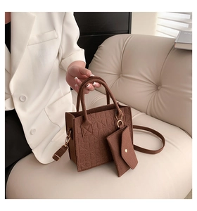 Detail of brown felt handbag with geometric embossing and matching small zipper pouch