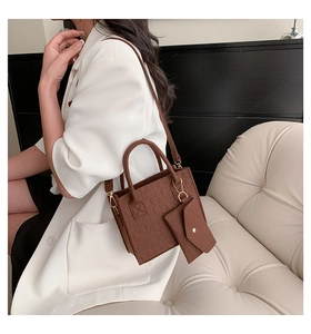 Deep brown embossed leather tote bag with matching small coin purse shown on a model