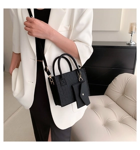 Detail of black felt tote bag with embossed clover pattern and matching envelope pouch