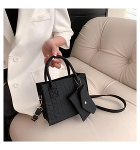 Detail of black embossed felt tote bag with matching chain pouch and gold-tone hardware