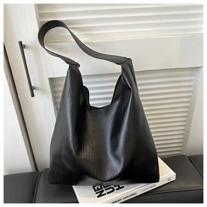 Détail du sac cabas en similicuir noir montrant la texture souple et la bandoulière