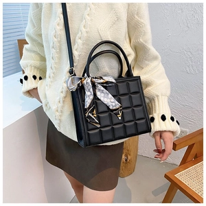 Detailed view of black textured tote bag with elegant polka dot scarf handle